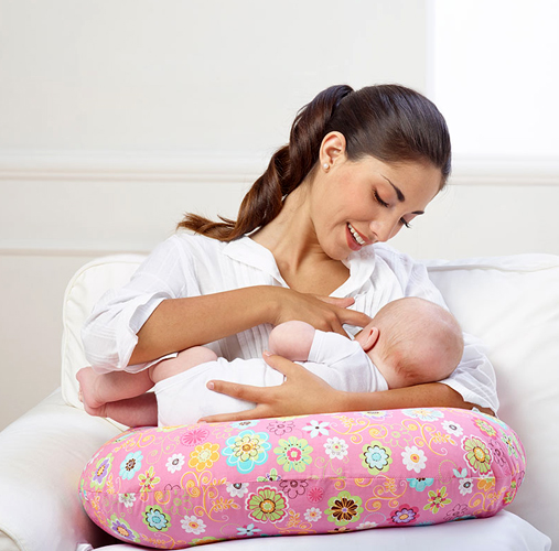 Mãe amamentando o bebê sentada no sofá, ilustrando dor na coluna durante a gestação e no pós-parto