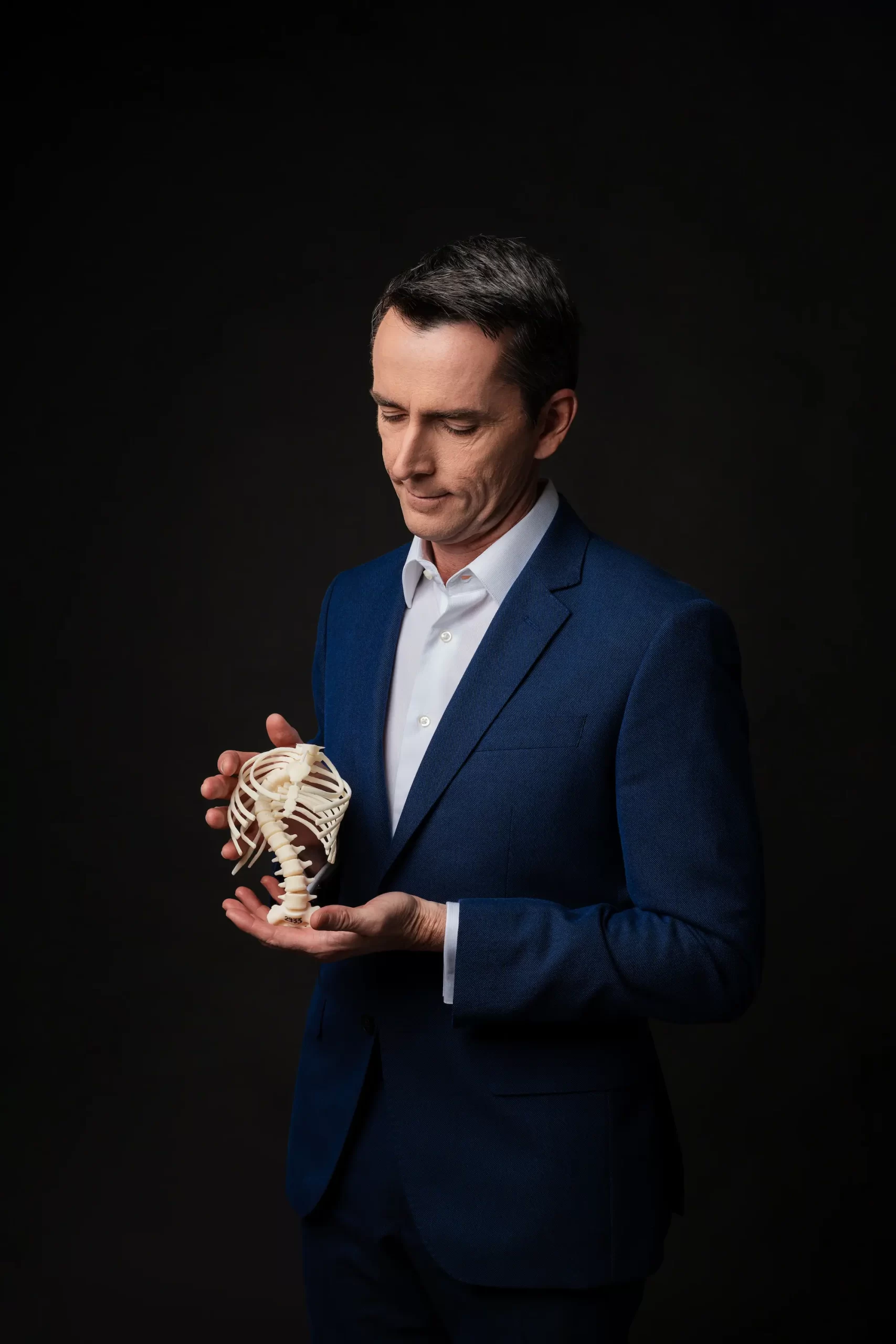 Imagem do Dr. Alexandre Jaccar segurando um biomodelo com deformidades da coluna.