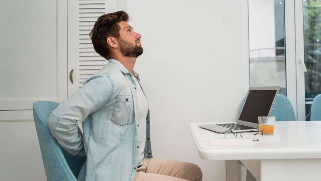 um homem sente dores nas costas no trabalho.