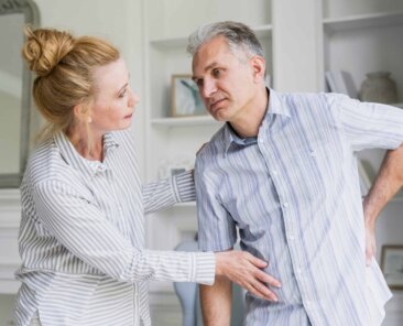 Um homem sofre com escoliose e é ajudado pela esposa.