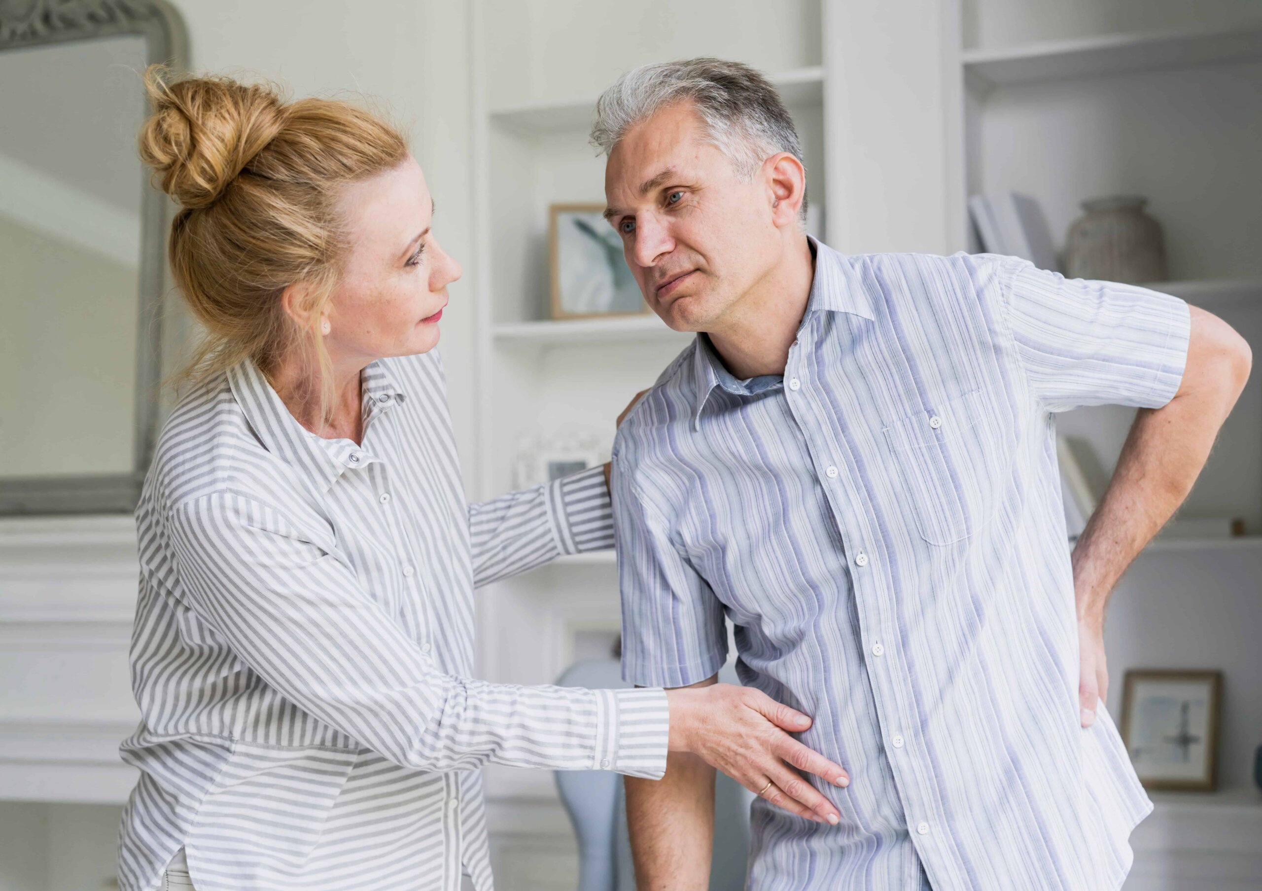 Um homem sofre com escoliose e é ajudado pela esposa.