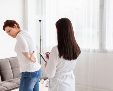 Uma mulher com dor nas costas é avaliada por médica especialista.