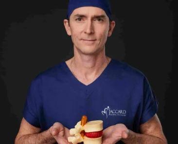 Dr. Alexandre Jaccard, ortopedista online, segurando um modelo anatômico da coluna vertebral e disco intervertebral