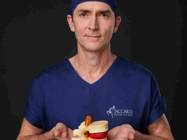 Dr. Alexandre Jaccard, ortopedista online, segurando um modelo anatômico da coluna vertebral e disco intervertebral