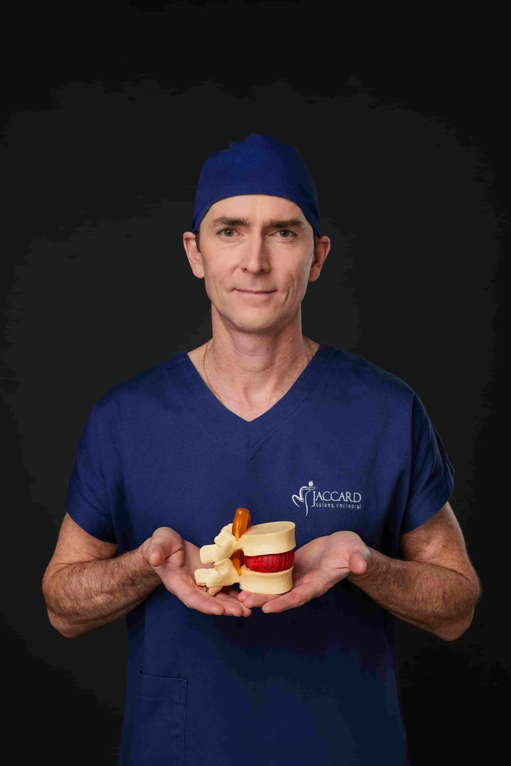 Dr. Alexandre Jaccard, ortopedista online, segurando um modelo anatômico da coluna vertebral e disco intervertebral